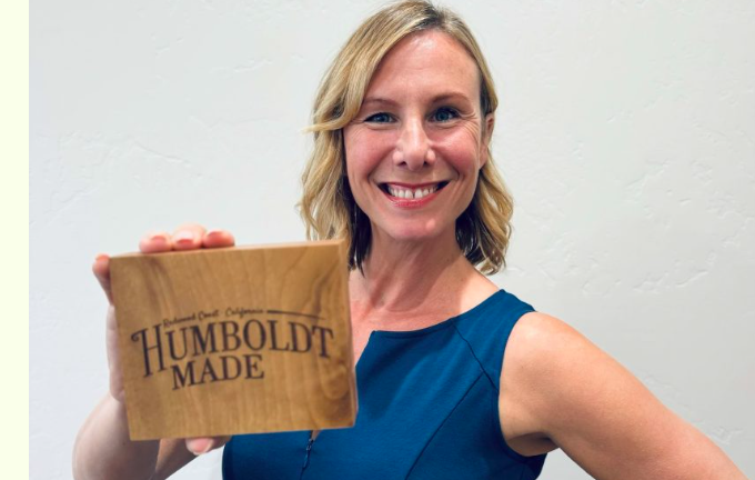 smiling woman holding wooden block with the Humboldt made logo on it.