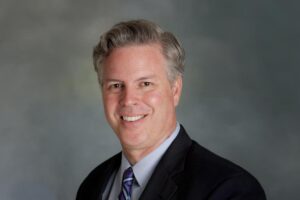 middle aged man in suit and tie posing for a professional portrait