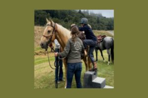 girl getting on a horse as a woman helps