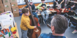 kid playing a cello in a classroom with other kids